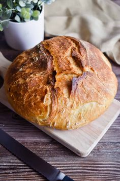 a loaf of bread sitting on top of a wooden cutting board next to a knife