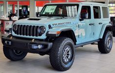 a light blue jeep is parked in a showroom