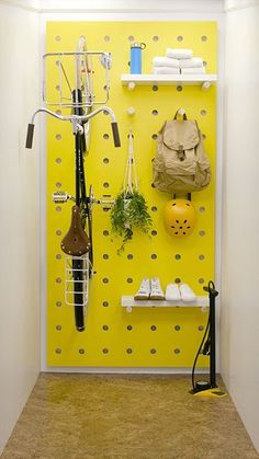 a yellow wall with hooks and shoes on it, next to a bike rack filled with items