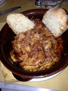 a bowl filled with meat and bread on top of a table