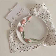 a white plate topped with pink flowers on top of a table next to a napkin