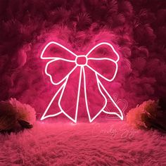 a pink neon sign with a bow on it