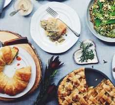 a table topped with lots of different types of pies and pastries on white plates