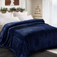 a bed covered in a blue blanket next to a christmas tree