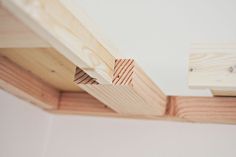 the corner of a wooden beam with wood slats on it's sides and one piece of wood sticking out from underneath