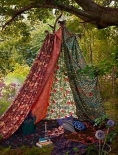 a tent is set up in the middle of a forest with flowers and trees around it