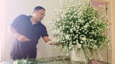 a man standing next to a vase filled with white flowers