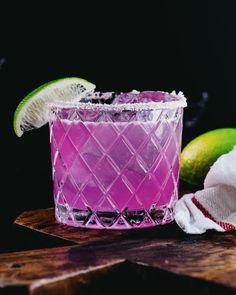 a pink cocktail with limes and sugar on the rim