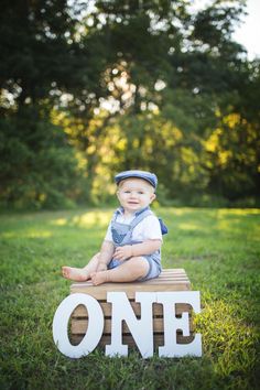 a little boy sitting on top of a wooden one sign