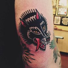 a cat tattoo on the leg of a man's arm, showing his teeth and tongue