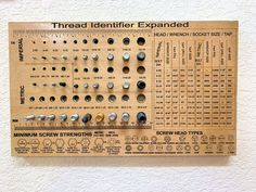 a wooden ruler with screws on it mounted to the side of a white wall