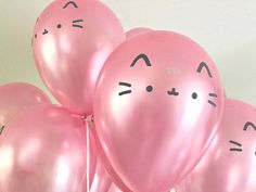 a bunch of pink balloons with faces drawn on them