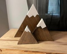 three wooden mountain sculptures sitting on top of a table