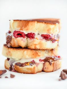 two sandwiches stacked on top of each other with raspberries and chocolate chips around them