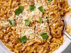 a white bowl filled with pasta covered in sauce and parmesan cheese