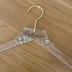 a clear plastic hanger with the word bridesmaid on it and flowers painted on it