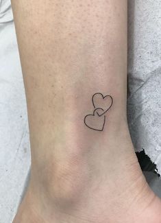 a small tattoo on the ankle of a woman's foot with two hearts in it