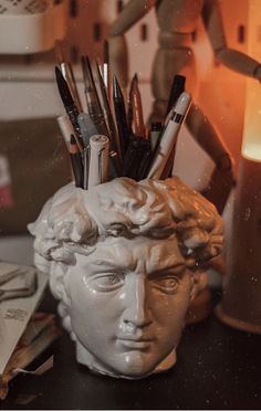 a statue head with pens and pencils in it