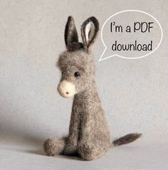 a small stuffed donkey sitting on top of a white floor next to a gray wall