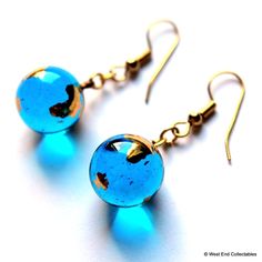 A stunning pair of earrings made with a mounted pair of miniature gold Earth Marbles. The suspended Earth Globes measure 12mm (0.5") diameter and; with geographic accuracy, depict the continents of the world in bright 22ct Gold. High quality Marbles are finished in coloured glass, in direct light they shine a most beautiful crystal blue. An exceptionally attractive set, an ideal gift for someone special. Telescope Astronomy, Continents Of The World, David Marks, Marble Earrings, Coloured Glass, Globe Pendant, Glass Marbles, Fun Earrings, Planet Earth