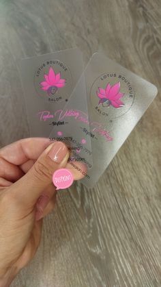 two stickers with pink flowers on them are being held by a woman's hand