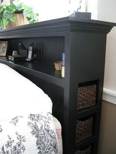 a bed with a black headboard and some baskets on the bottom shelf next to it