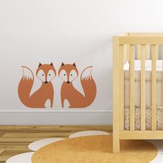 a baby's room with a crib and wall decal featuring two foxes