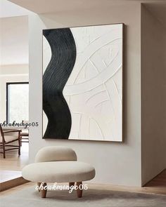 an abstract painting hangs on the wall in a living room with a chair and ottoman