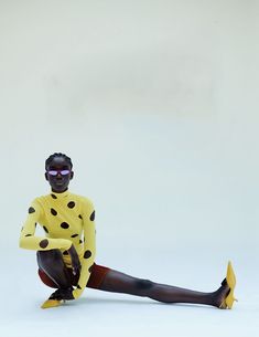 a woman in a yellow and black polka dot costume sitting on the ground with her legs crossed