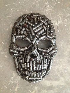 a mask made out of metal tubes on the ground with holes in it's face