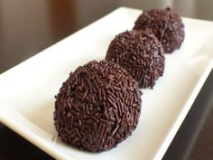 three chocolate donuts on a white plate