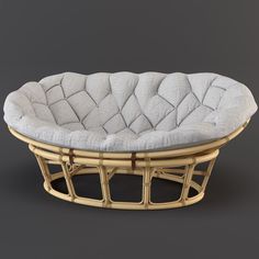 a round wicker bed with white pillows on the top and bottom, sitting in front of a gray background