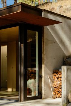 the entrance to a modern home with wood stacked outside