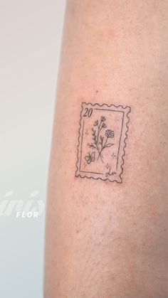 a small stamp with flowers on the back of a woman's arm that is covered in black ink