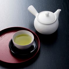 a white tea pot sitting on top of a red plate