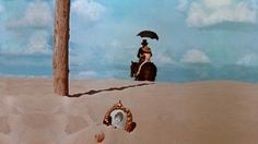 a woman sitting on top of a horse under an umbrella in the sand next to a mirror