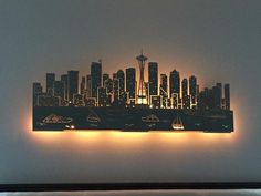 a city skyline lit up at night with lights in the foreground and on the wall