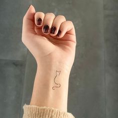 a woman's wrist with a cat tattoo on it