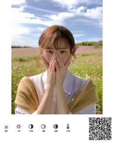 a woman covers her face with her hands while standing in a field full of flowers