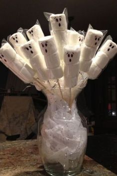 a glass vase filled with marshmallows and ghost faces on it's sides