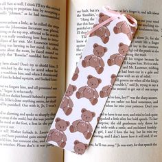 a bookmark with a teddy bear pattern on it sitting next to an open book