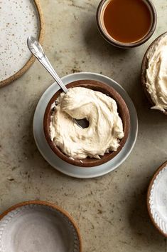 a table topped with plates and bowls filled with desserts covered in frosted cream