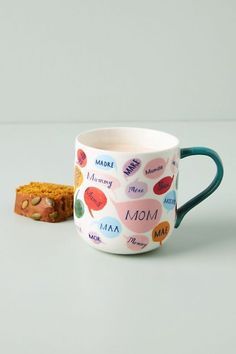 a coffee cup with the words mom on it next to a cookie