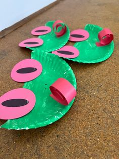 two paper plates with pink and green designs on them sitting on the ground next to each other