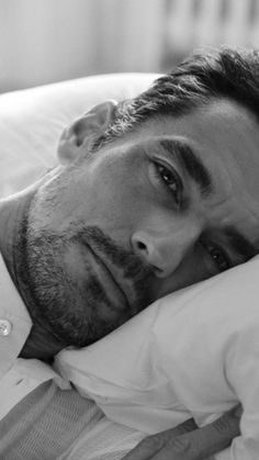 a man laying in bed with his head on the pillow