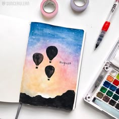 an open notebook with two hot air balloons floating in the sky and another drawing on it