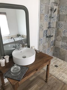 a bathroom with a sink, mirror and tiled shower stall in it's corner