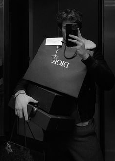 a man is taking a selfie with his cell phone while holding a shopping bag