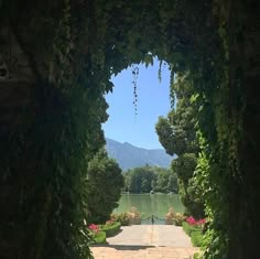 an archway leading to a lake surrounded by greenery