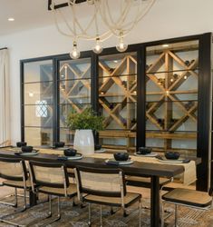 the dining room table is set with black and white plates, glasses, and vases